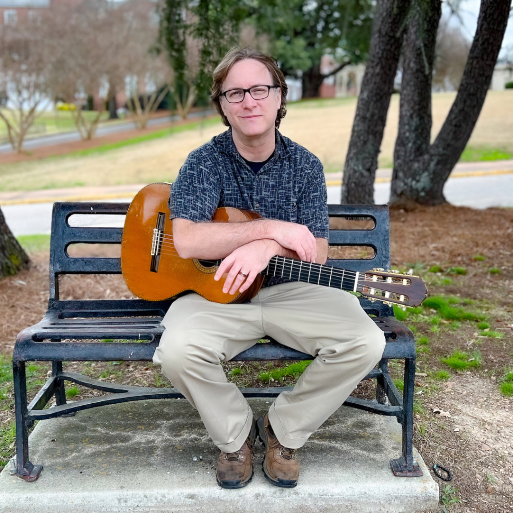 Bobby Hall sitting on bench holding guitar