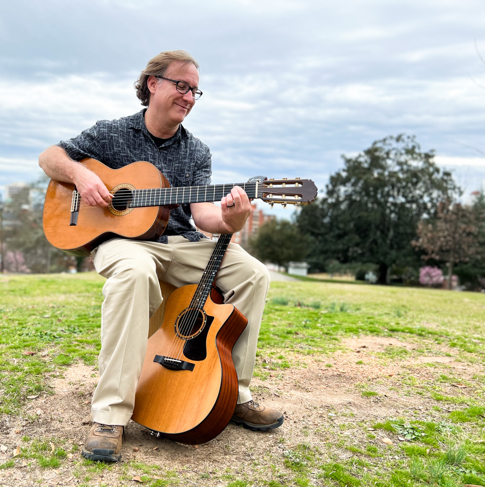 Bobby Hall outside with an acoustic guitar and a classical guitar